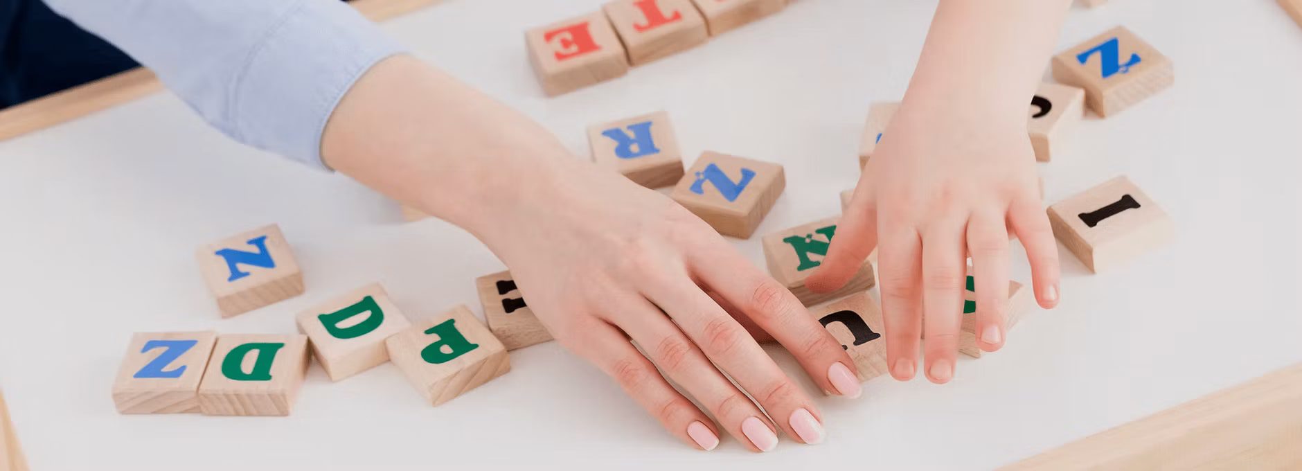 Adult helping a child learn using letter blocks